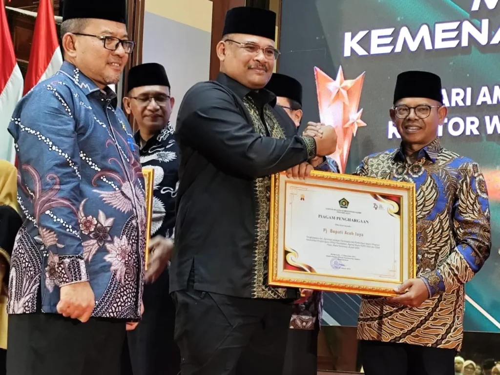 Foto: Pj Gubernur Aceh, Dr. H. Safrizal ZA, M.Si, didampingi oleh Kakanwil Kemenag Aceh, Drs. H. Azhari, M.Si. Menyerahkan penghargaan kepada Penjabat Bupati Aceh Jaya, Dr. A. Murtala, M.Si