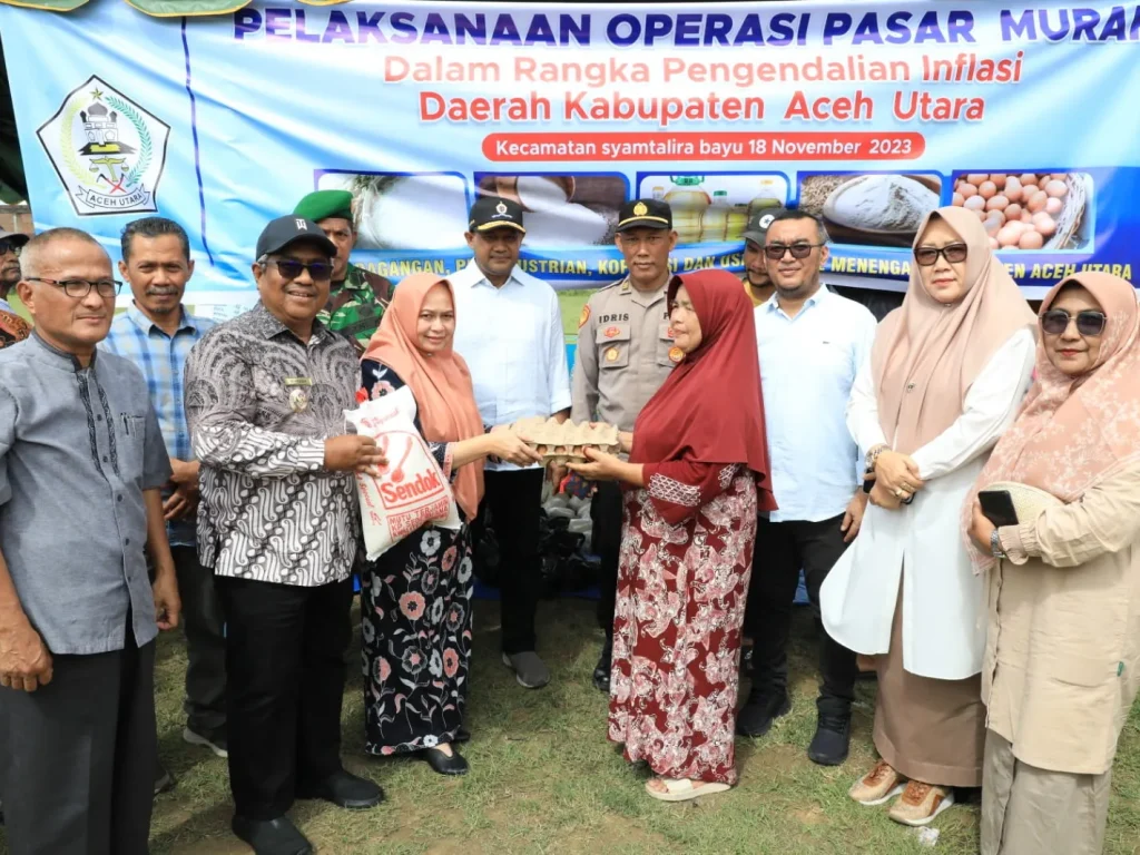 Foto: Penjabat Bupati Aceh Utara, Dr. Drs. Mahyuzar M.Si didampingin ketua Bunda Paud Ny Awirdalina Mahyuzar menyerahkan Bahan Pokok Warga pada Gelar Pasar Murah