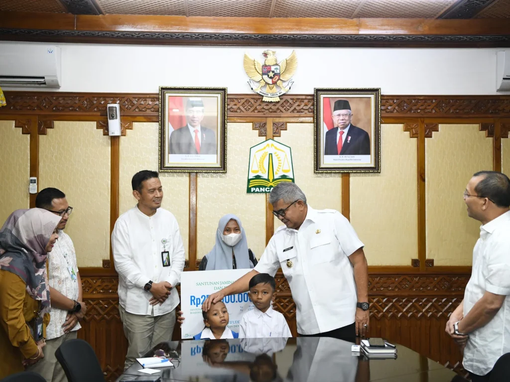 Foto: Pj Gubernur Aceh Bustami, SE, M.Si  didampingi Direktur Keuangan BPJS Ketenagakerjaan, menyerahkan Santunan Jaminan Kematian dan Beasiswa kepada kepada Istri dan Anak Almarhum Yusri Afifuddin di Ruang Rapat Gubernur Aceh 22/03/2024