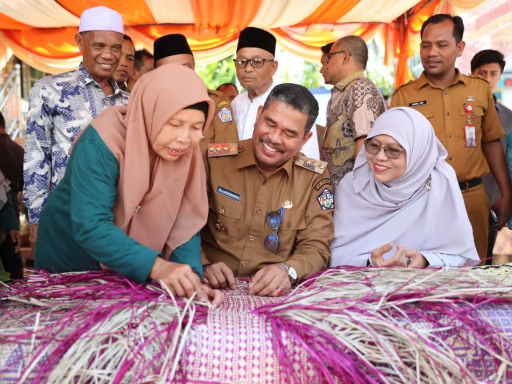 Foto: Pj Walikota Lhokseumawe, A. Hanan, SP, MM, mencoba menyulam anyama tikar bersama perajin