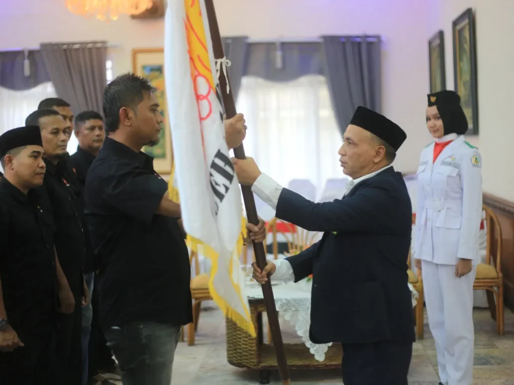 Foto: Ketua KONI Aceh H Kamaruddin Abubakar menyerahkan Bendera Pataka Kepada Ketua Terpilih M Dahlan Ishak