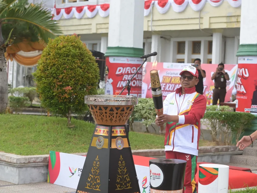 Foto: Pj. Bupati Aceh Jaya, Dr. A. Murtala menyalakan kembali Api untuk diserahkan kembali kepada pelari kirab Api PON XXI di halaman Kantor Bupati Aceh Jaya, 27/8/2024